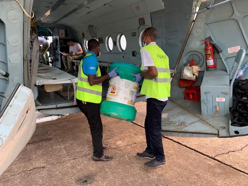 Workers carry an Arktek ultra-cold vaccine storage cylinder containing Ebola vaccines onto a helicopter in Mbandaka