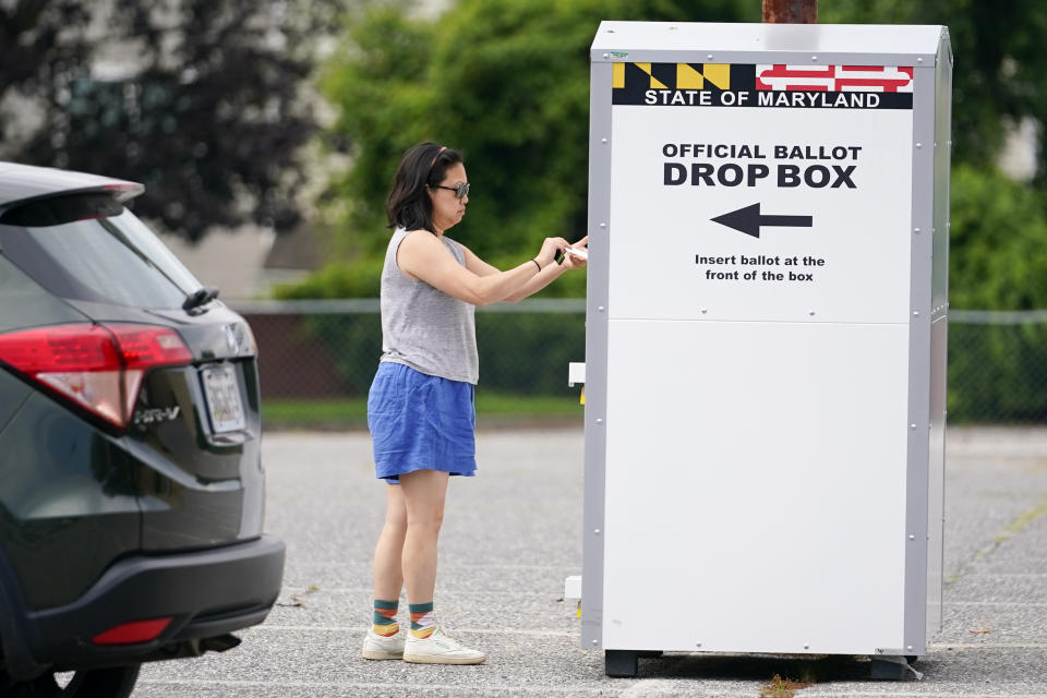 FILE - A woman drops a ballot into a drop box while casting her vote during Maryland's primary election, Tuesday, July 19, 2022, in Baltimore. On Friday, Nov. 11, The Associated Press reported on stories circulating online incorrectly claiming a candidate winning an election with a majority of mailed ballots is proof of fraud. (AP Photo/Julio Cortez, File)