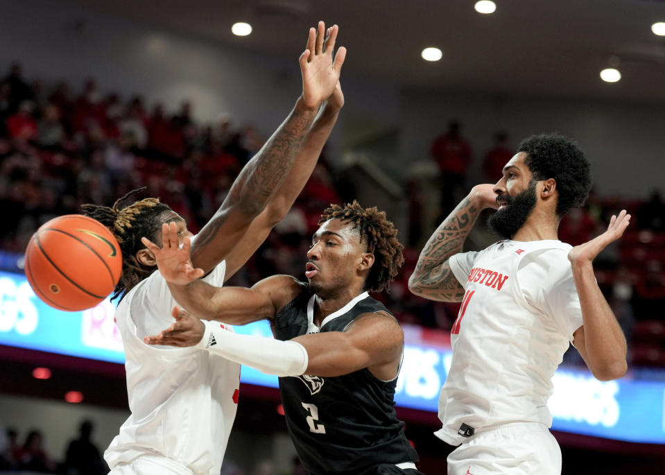 Rice guard Mekhi Mason (2) passes between Houston forward Ja'Vier Francis (5) and guard Damian Dunn (11) during the first half of an NCAA college basketball game at the Fertitta Center, Wednesday, Dec. 6, 2023, in Houston. (Jason Fochtman/Houston Chronicle via AP)
