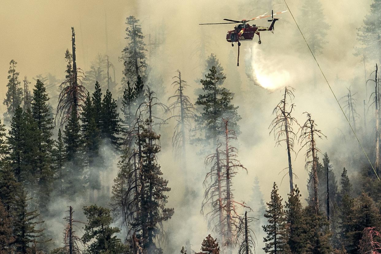 Seen from unincorporated Mariposa County, Calif., a helicopter drops water on the Washburn Fire burning in Yosemite National Park, Saturday, July 9, 2022.