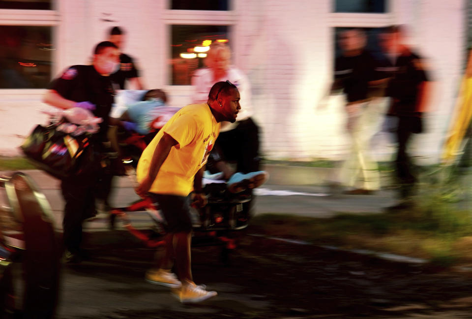 Emergency response crews move wounded people to ambulances after multiple people were shot at a party Saturday, June 20, 2020, in Syracuse, N.Y. Nine people were shot and one victim, a 17-year-old boy, was in critical condition Sunday. (Ellen M. Blalock/Syracuse Post-Standard via AP)