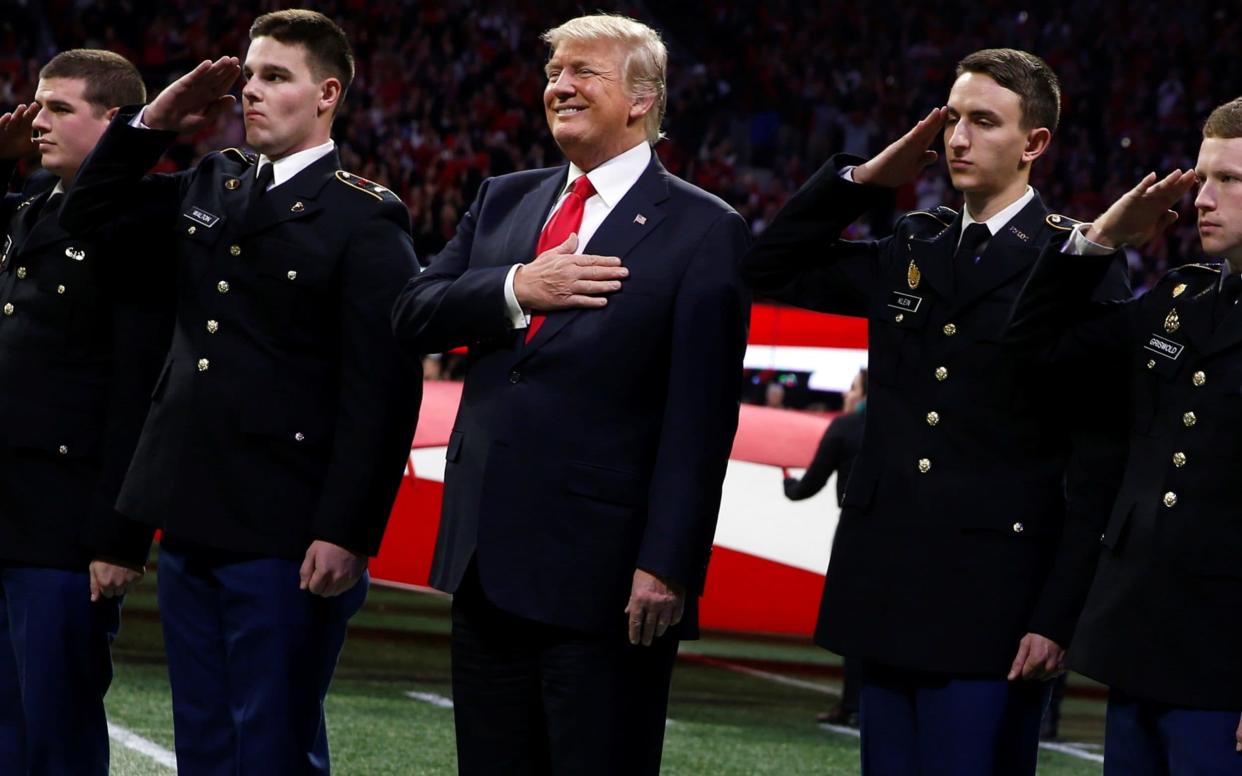 President Donald Trump stands with ROTC students to participate in the national anthem before the NCAA College Football Playoff Championship game between Alabama and Georgia in Atlanta - REUTERS