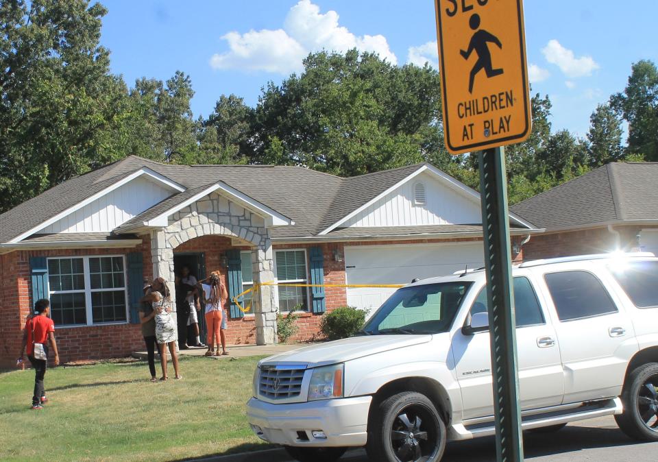 People gathered in the front yard of a home where a child was found in a hot car Tuesday. The child died at a hospital, police said.