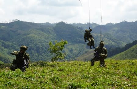 Soldiers disembark from a helicopter as workers destroy coca plants during an eradication operation at a plantation in Taraza