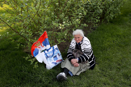 A woman sits on the lawn waiting to attend Serbian President Aleksandar Vucic campaign rally "The Future of Serbia" in front of the Parliament Building in Belgrade, Serbia, April 19, 2019. REUTERS/Marko Djurica