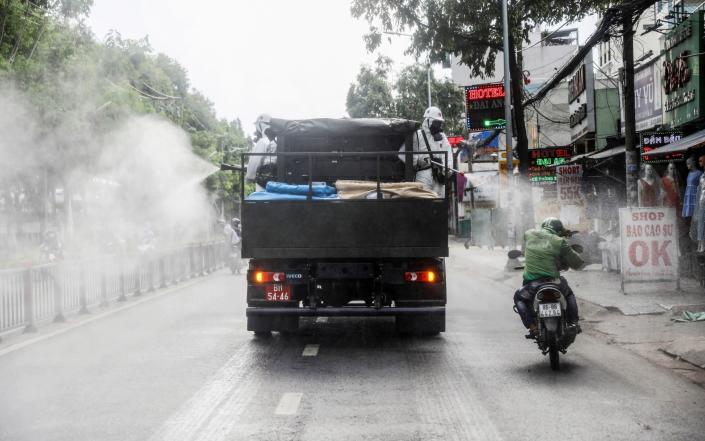 A truck sprays disinfectant against coronavirus, catching a passing motorcyclist off-guard in Ho Chi Minh city, Vietnam - Stringer/REUTERS