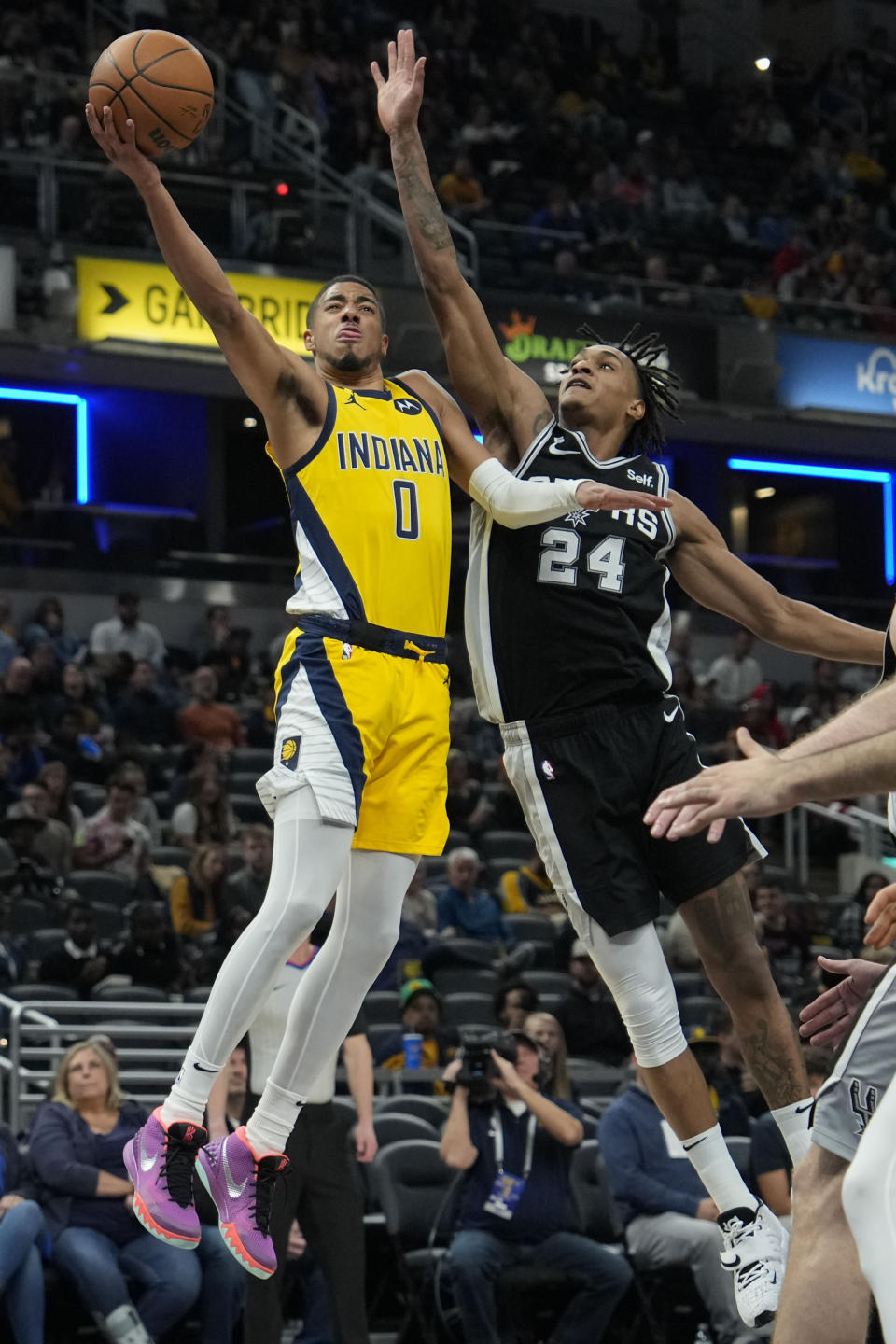 Indiana Pacers guard Tyrese Haliburton (0) shoots under the defense of San Antonio Spurs guard Devin Vassell (24) during the second half of an NBA basketball game in Indianapolis, Friday, Oct. 21, 2022. (AP Photo/AJ Mast)
