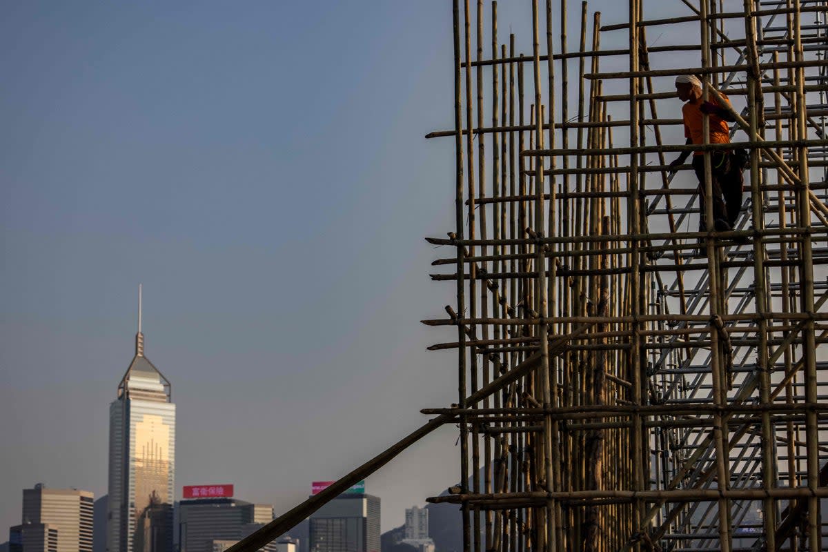 This picture taken on 1 March 2023 in Hong Kong, said to be the world’s most skyscraper-laden metropolis, shows a scaffolder standing on bamboo scaffolding (AFP via Getty Images)