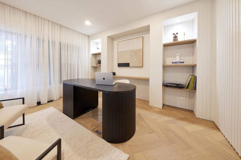 A wide shot of the study, with the desk in the centre, bookshelves either side on the back wall. 