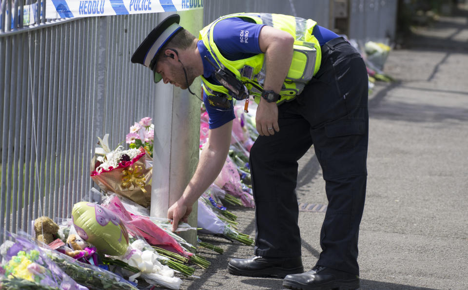 An officer lays floral tributes at the scene on Brithweunydd Road in Trealaw where 4-year-old Amelia Brooke Harris was found dead on June 11. Image: Getty
