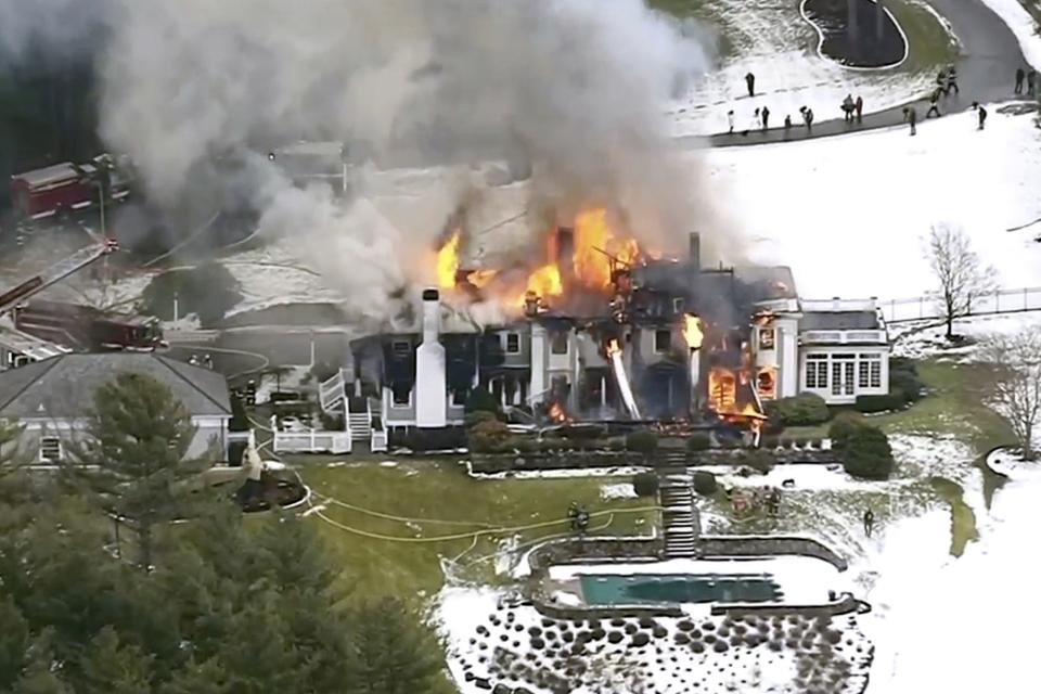 This aerial still image from video provided by WCVB shows a mansion ablaze Friday, Dec. 27, 2019, in Concord, Mass. Firefighters are battling a blaze at the mansion in the Boston suburbs, as flames can be seen shooting out of the roof of the 6,500-square-foot home. (WCVB-TV via AP)