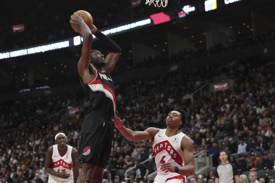 Portland Trail Blazers forward Jerami Grant, top, goes up to dunk over Toronto Raptors forward Scottie Barnes (4) during second-half NBA basketball game action in Toronto, Monday, Oct. 30, 2023. (Nathan Denette/The Canadian Press via AP)