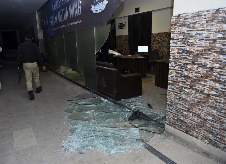 A police officer walks past a damage area after security forces conducting operation against attackers at a police headquarters, in Karachi, Pakistan, Friday, Feb. 17, 2023. Militants launched a deadly suicide attack on the police headquarters of Pakistan's largest city on Friday, officials said, as the sound of gunfire and explosions rocked the heart of Karachi for several hours. (AP Photo/M. Noman)