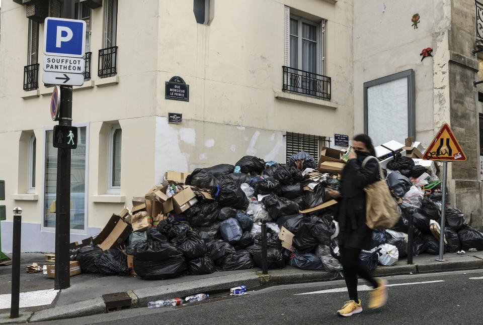 ARCHIVO - Una mujer se cubre la nariz mientras pasa junto a un montón de basura en París, el lunes 20 de marzo de 2023. durante una huelga prolongada de servicios de limpieza. (AP Foto/Aurelien Morissard, Archivo)