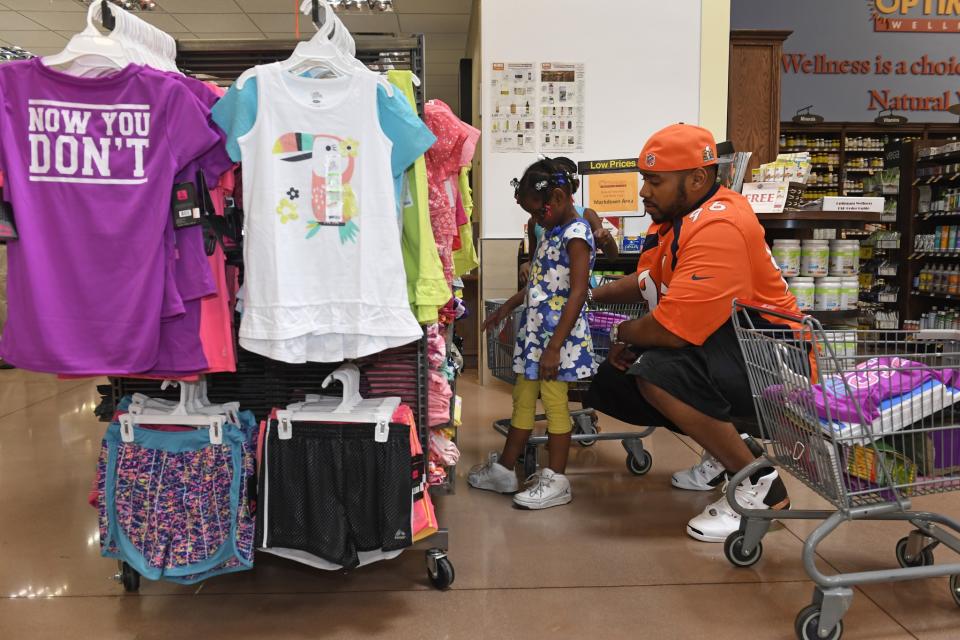 <p>Denver Broncos defensive end Vance Walker, #96 helps Brooklyn Hill, 6, in floral, pick out some clothes as they shop at King Soopers Marketplace on July 25, 2016 in Parker, Colorado. </p>