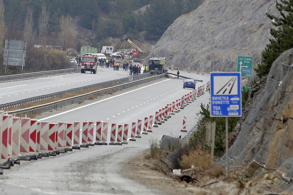 A motorway is cordoned off after a bus, seen at center, crashed overnight near the village of Bosnek, western Bulgaria early Tuesday, Nov. 23, 2021. A bus carrying North Macedonians home from a tourist trip to Istanbul crashed and caught fire in western Bulgaria early Tuesday, killing at least 45 people, authorities and local media said. (AP Photo/Valentina Petrova)