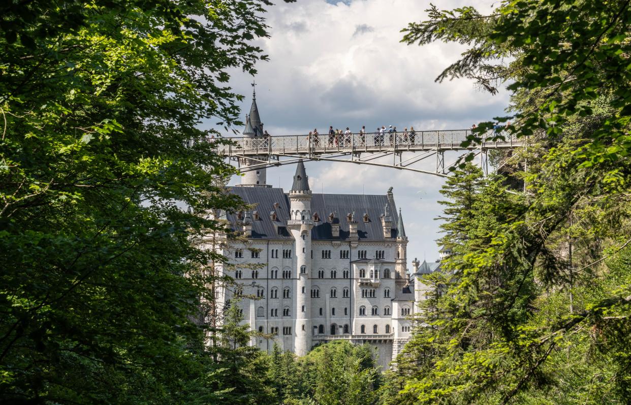 image of the castle behind a foot bridge with tourists on it