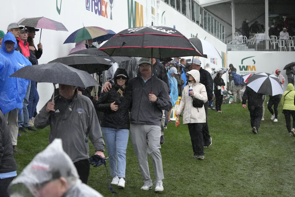 Fans in the gallery leave the ninth hole as rain pours down during the first round of the Phoenix Open golf tournament Thursday, Feb. 8, 2024, in Scottsdale, Ariz. (AP Photo/Ross D. Franklin)