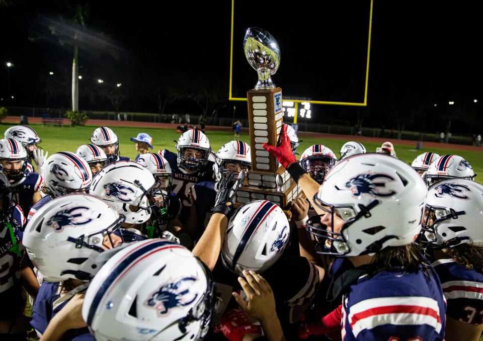 The Estero High School football team celebrates with a trophy after defeating Bonita Springs High School in the annual Jaws vs. Claws rivalry game at Estero on Friday, Nov. 3, 2023.