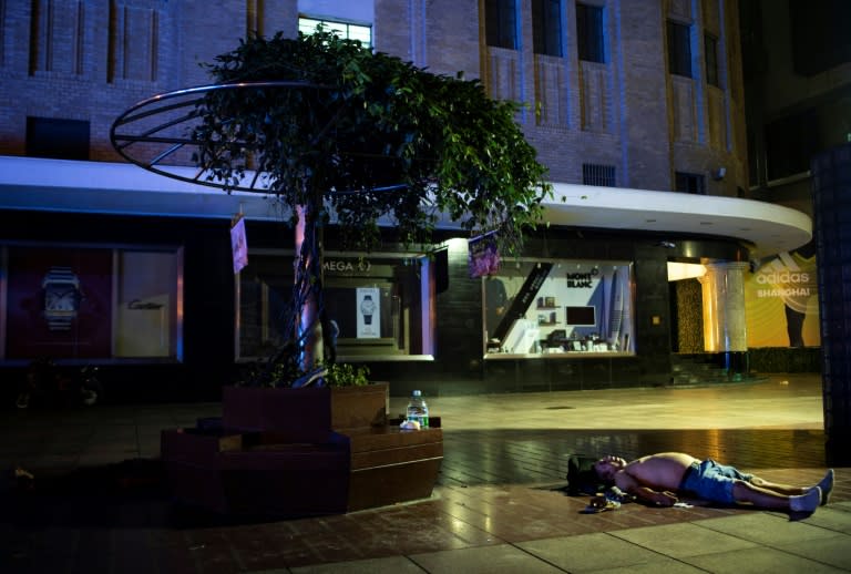 As Shanghai temperatures soar, a number of men choose a cool outdoor stretch of pavement as a bed