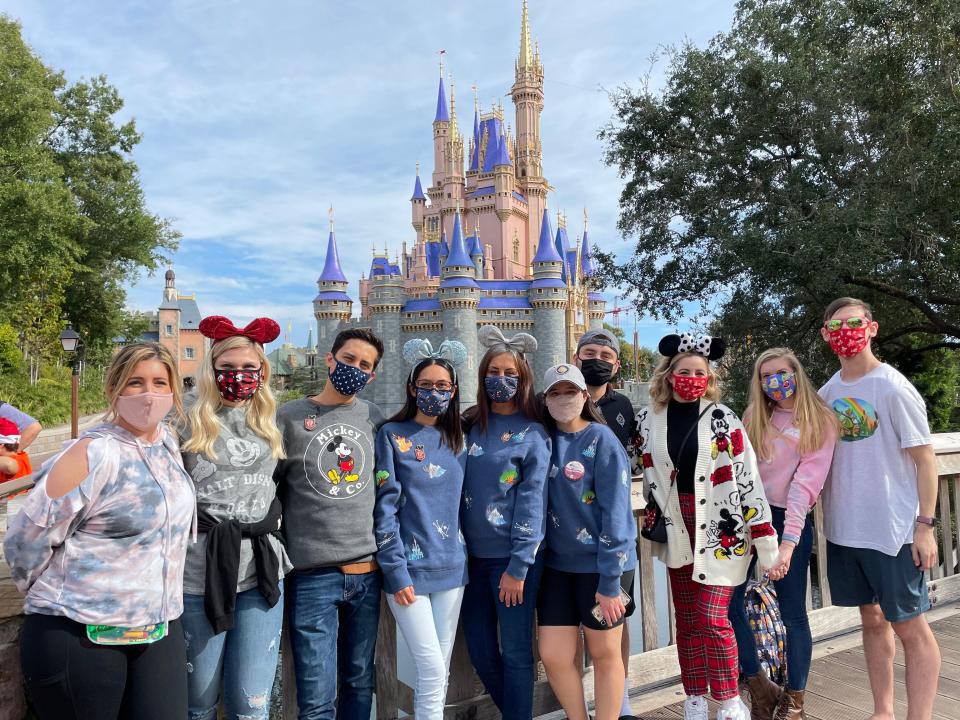 josie and her group posing in front of the castle at disney world during a vip tour