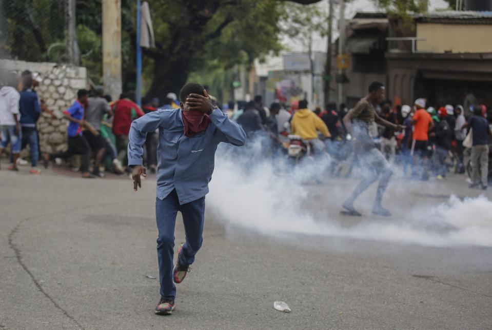A protester run from tear gas fired by riot police officers during a demonstration demanding the resignation of Prime Minister Ariel Henry in Port-au-Prince, Haiti, Wednesday, Feb. 7, 2024. (AP Photo/Odelyn Joseph)