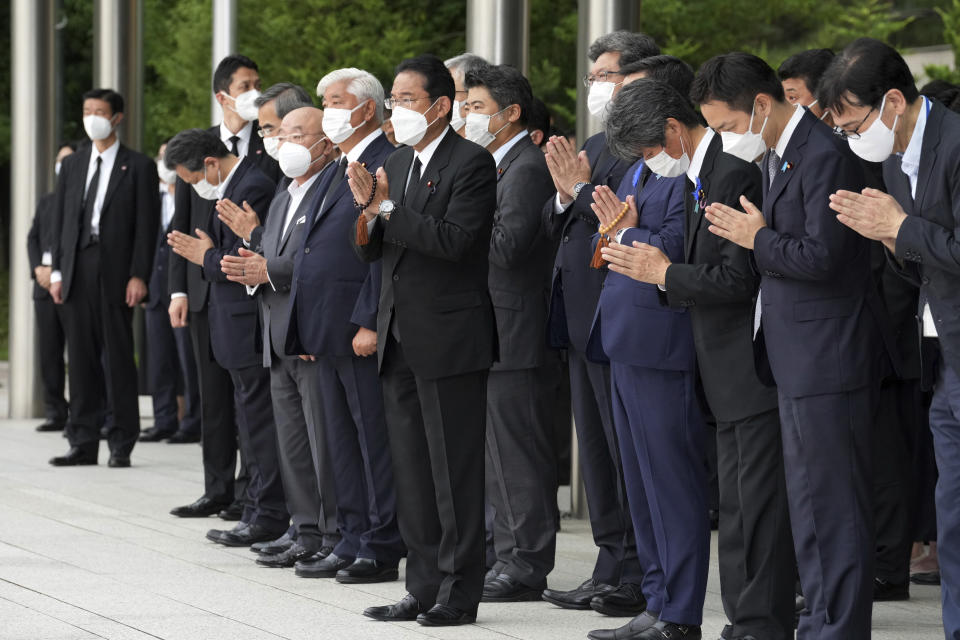 Japan's Prime Minister Fumio Kishida, center, officials and employees offer prayers towards a hearse carrying the body of former Prime Minister Shinzo Abe, as the vehicle makes a brief visit to the Prime Minister's Office Tuesday, July 12, 2022, in Tokyo. (AP Photo/Eugene Hoshiko, Pool)