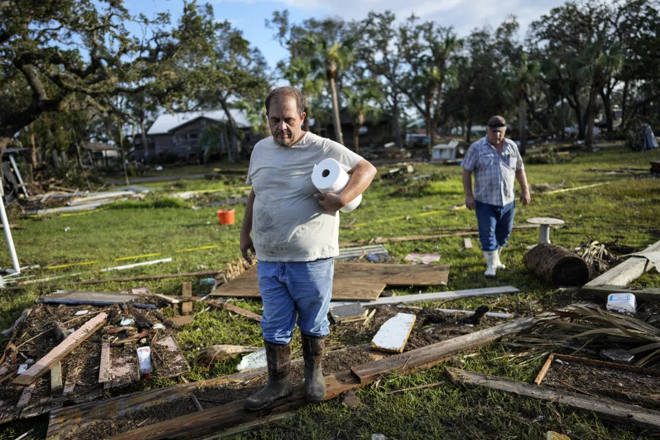 Image: Buddy Ellison, left, and his father Dan look through debris scattered across their property in Horseshoe Beach, Fla., on Aug. 31, 2023, one day after the passage of Hurricane Idalia.  (Rebecca Blackwell / AP)