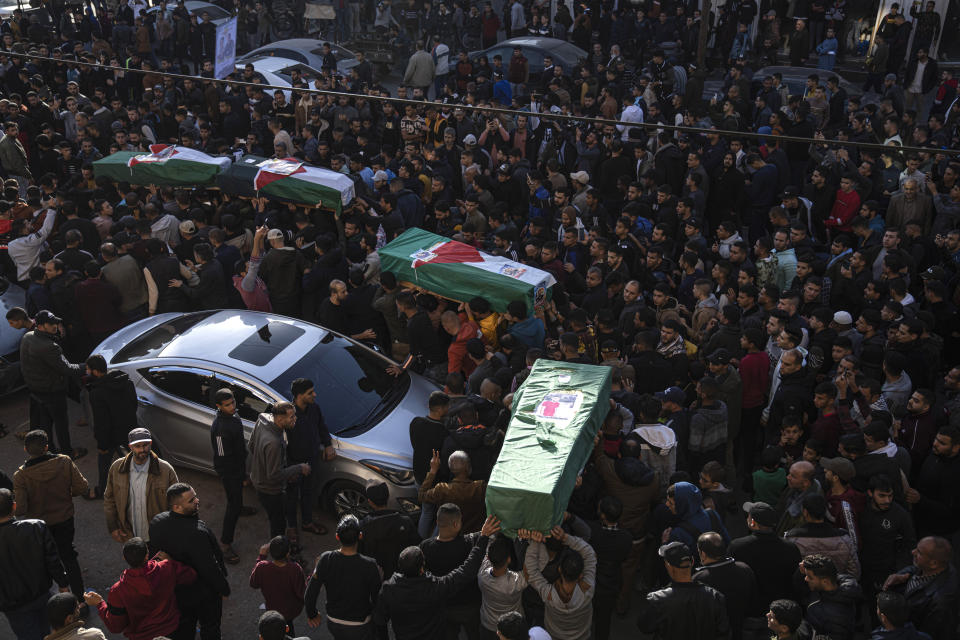 Palestinians carry the bodies of four Palestinian migrants who died off the Tunisian coast, in Rafah in the southern Gaza Strip, Sunday, Dec. 18, 2022. Thousands of people have joined the funerals of eight young Palestinian men who drowned off the coast of Tunisia nearly two months ago as they tried to sail to new lives in Europe. (AP Photo/Fatima Shbair)