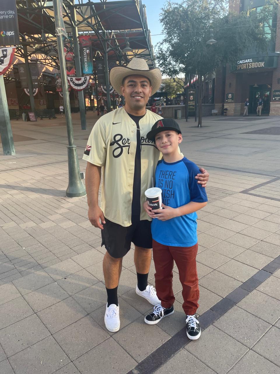 Sporting a Diamondbacks “Serpientes” jersey, Gerardo Padilla and his son attend Game 3 against the Phillies at Chase Field on Oct. 19, 2023.