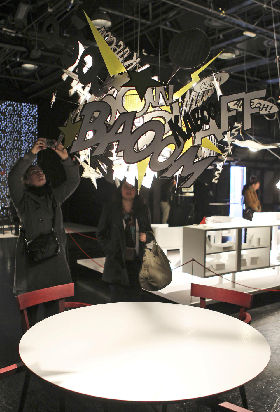 In this Friday, April 20, 2012 photo a woman photographs the "Comic Explosion" lamp by German designer Ingo Maurer at the Milan's Furnishing Accessories Exhibition, in Milan, Italy. The Milan Furniture Fair, a six-day event which ended Sunday, was full of experiment and whimsy. (AP Photo/Antonio Calanni)