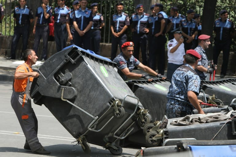 Police officers remove barricades erected by demonstrators protesting against electricity price hikes in central Yerevan on July 6, 2015