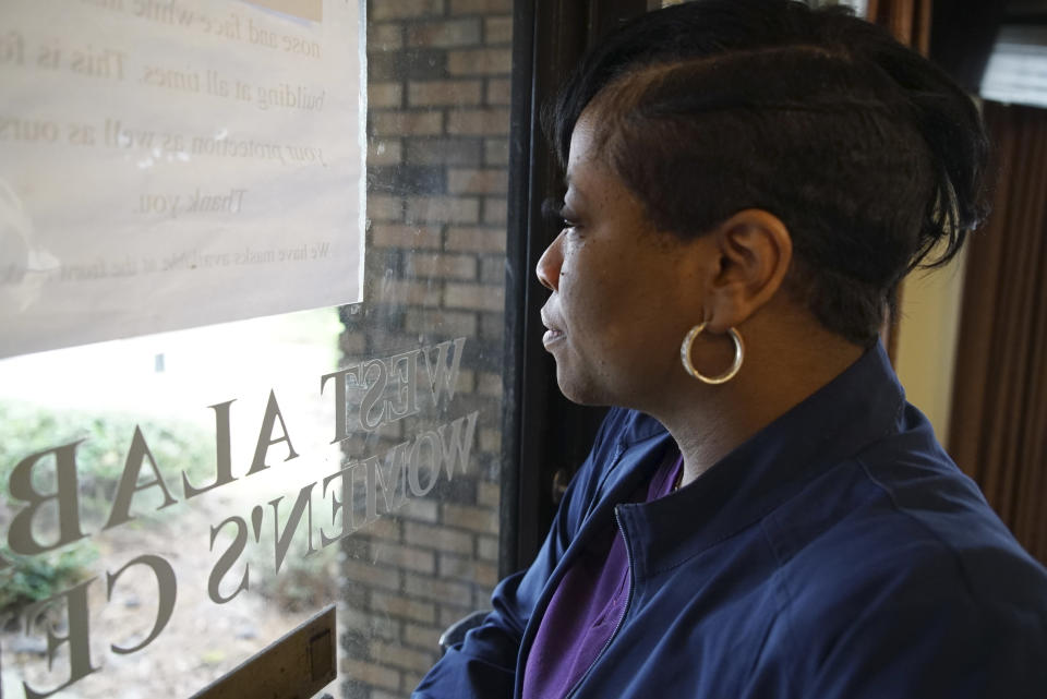 Alesia Horton, director of the West Alabama Women's Center in Tuscaloosa, Ala., looks out the window at protesters on Tuesday, March 15, 2022. A deeply religious woman, she says of those who picket the clinic: "God isn't theirs. God is all of ours." (AP Photo/Allen G. Breed)