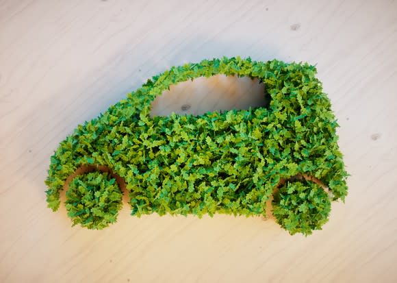 Green leaves form the shape of a car on a wooden background