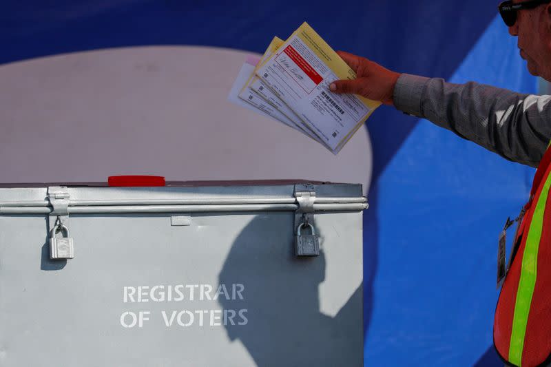 FILE PHOTO: An election worker places mail-in ballots into an election box at a drive-through drop off location at the Registrar of Voters in San Diego, California