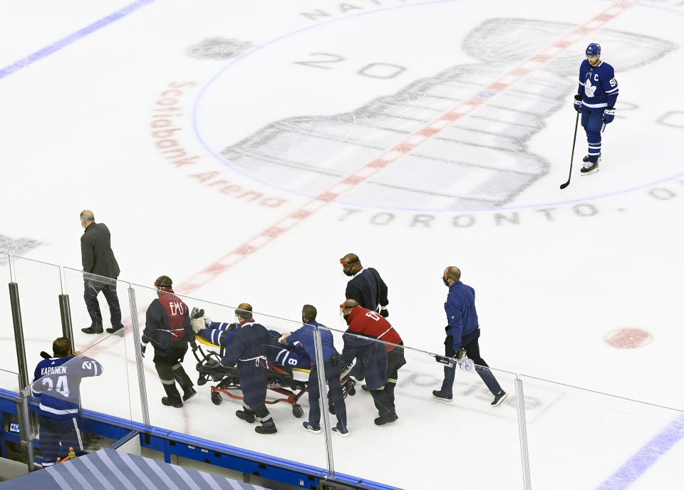 Toronto Maple Leafs captain John Tavares, top right, watches as his teammate Jake Muzzin leaves the ice on a stretcher while playing against the Columbus Blue Jackets during the third period of an NHL hockey playoff game Tuesday, Aug. 4, 2020 in Toronto. (Nathan Denette/The Canadian Press via AP)