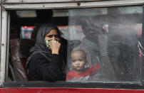 A woman and child look out the window of a a bus as they leave for their village following a six-day lockdown put into place to control the rising cases of coronavirus infections, in New Delhi, India, Tuesday, April 20, 2021. India recorded over 250,000 new infections and over 1,700 deaths in the past 24 hours alone, and the U.K. announced a travel ban on most visitors from the country this week. (AP Photo/Manish Swarup)
