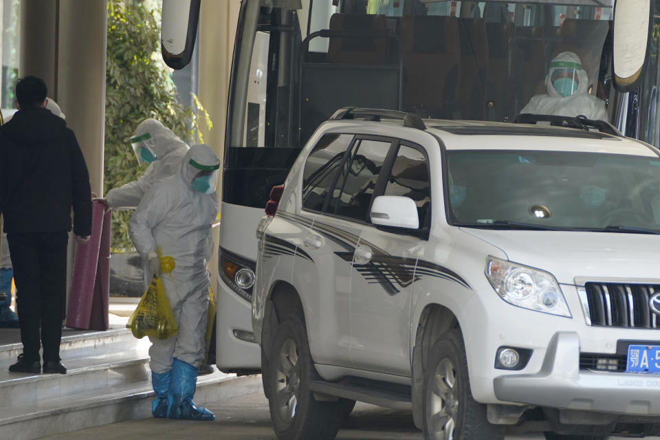 A worker in protective gear carries an exercise dumbbell belonging to the World Health Organization team of experts as they prepare to leave from a quarantine hotel in Wuhan in central China's Hubei province on Thursday, Jan. 28, 2021. (AP Photo/Ng Han Guan)