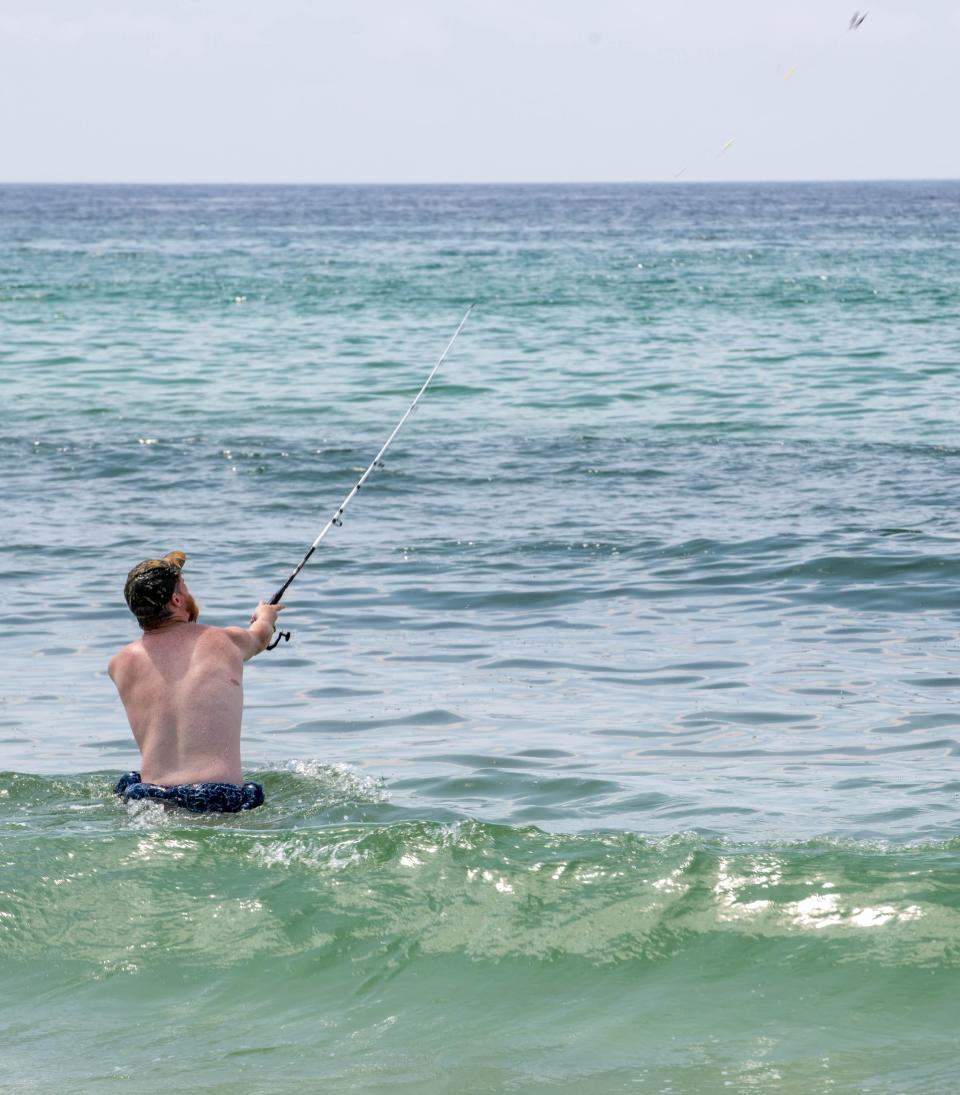 Philip Casey, of Coldwater, Mississippi, casts while fishing for catfish in the surf at Navarre Beach on Tuesday, July 11, 2023.
