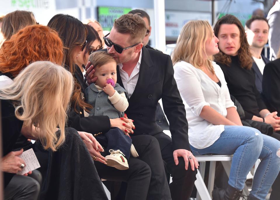 Macaulay Culkin (center) kisses his younger son's head as Catherine O'Hara, from left, Natasha Lyonne, Brenda Song, Quinn Culkin, and Rory Culkin attend a ceremony honoring Macaulay Culkin with a star on the Hollywood Walk of Fame on Dec. 1, 2023, in Los Angeles.