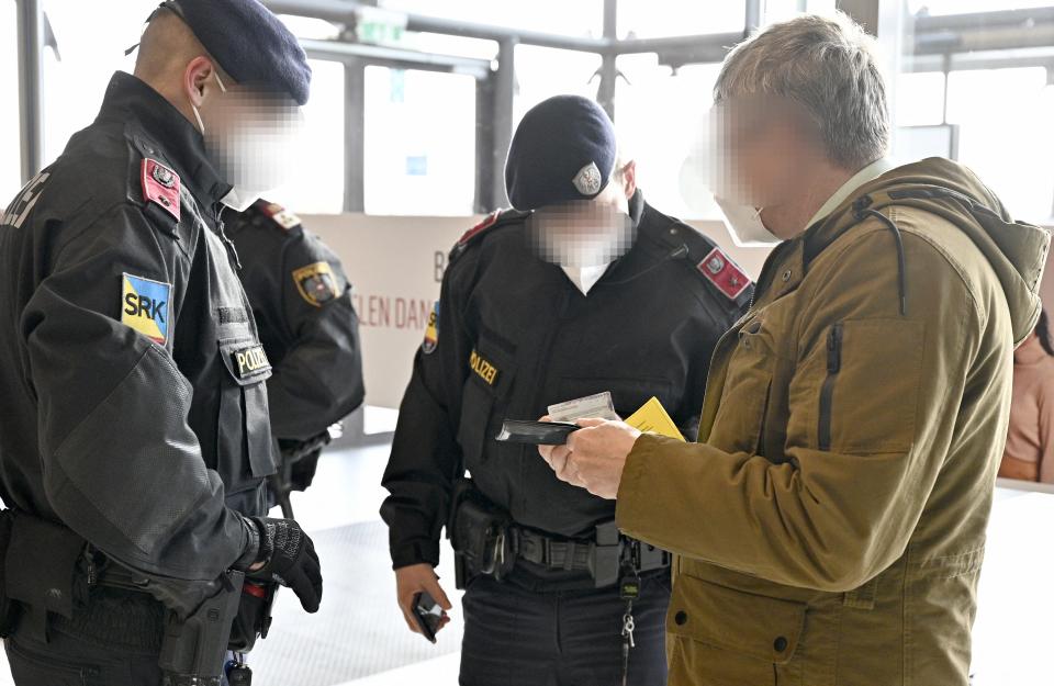 Austrian police officers check a man's identity and vaccination certificate during a control in Voesendorf, district Moedling, Austria, on November 16, 2021, during the ongoing coronavirus (Covid-19) pandemic. - Austrian Chancellor Schallenberg told AFP that the 