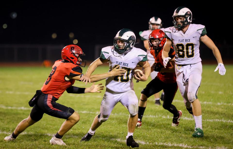 Brian Booms of Flat Rock tries to elude Milan's KJ DeMars during a 49-21 Flat Rock win Friday night. Booms broke his own school record with six touchdowns in the game.