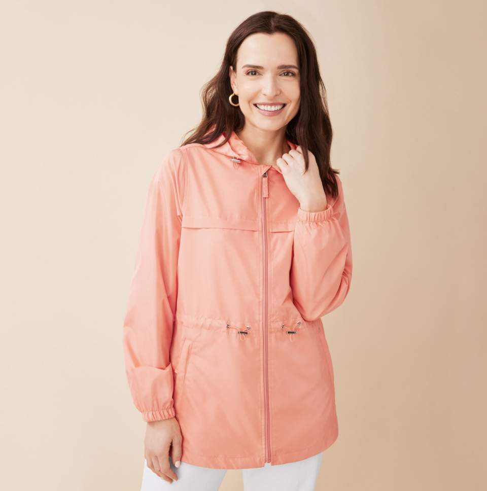 brunette model wearing peach pink Packable Wind Jacket and white pants (photo via Northern Reflections)