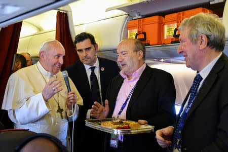 Pope Francis hands a cake to two reporters who both celebrated their birthdays while covering the Pope's trip, within addressing reporters aboard the plane bringing him back following a two-day trip to Morocco on March 31, 2019. Alberto Pizzoli/Pool via REUTERS