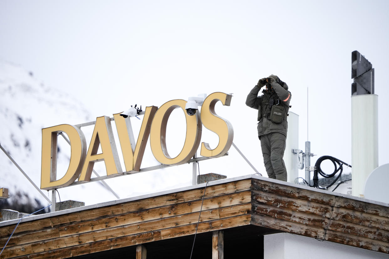 A police officer stands on the roof of a hotel and monitore the area with a binocular in Davos, Switzerland Monday, Jan. 16, 2023. The annual meeting of the World Economic Forum is taking place in Davos from Jan. 16 until Jan. 20, 2023. (AP Photo/Markus Schreiber)