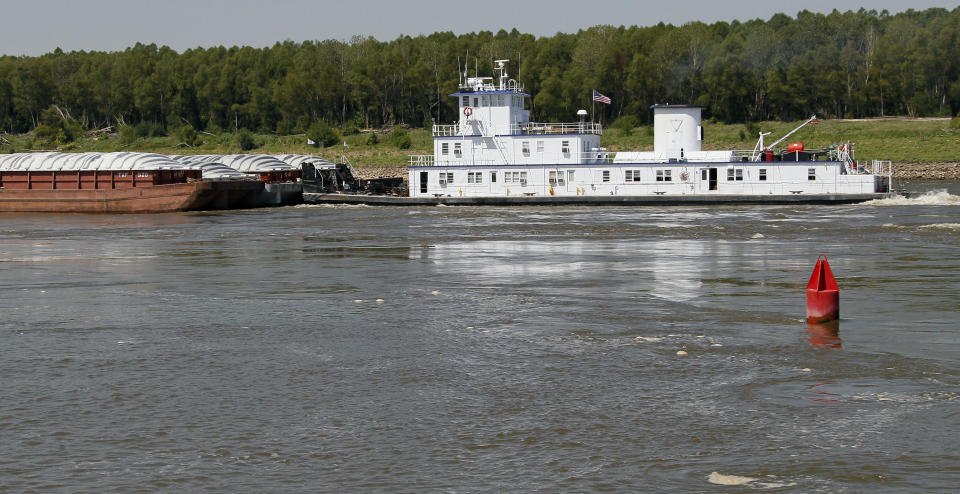 A river buoy floats in the Mississippi River as barges and their towboat float past it, Wednesday, Aug. 22, 2012 north of Greenville, Miss. The Dredge Jadwin, a U.S. Army Corps of Engineers vessel is clearing out some of the silt and left over mud and debris from last year's record flood on the Mississippi River and cutting a deeper channel for barges and their towboats to navigate north of Greenville. Coast Guard Capt. William Drelling said Wednesday that authorities would inspect the channel near Greenville, then reset navigation buoys allowing barge traffic to resume on a limited basis as both federal agencies deal with the continued drought that has lowered the Mississippi River. (AP Photo/Rogelio V. Solis)