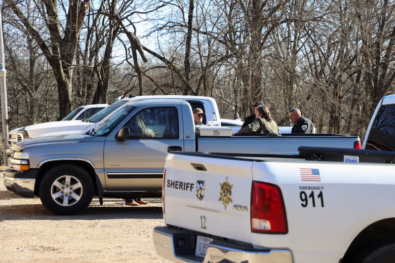 Law enforcement members gather next to the vehicle of the victim of a shooting outside a gas station convenience store in Arkabutla