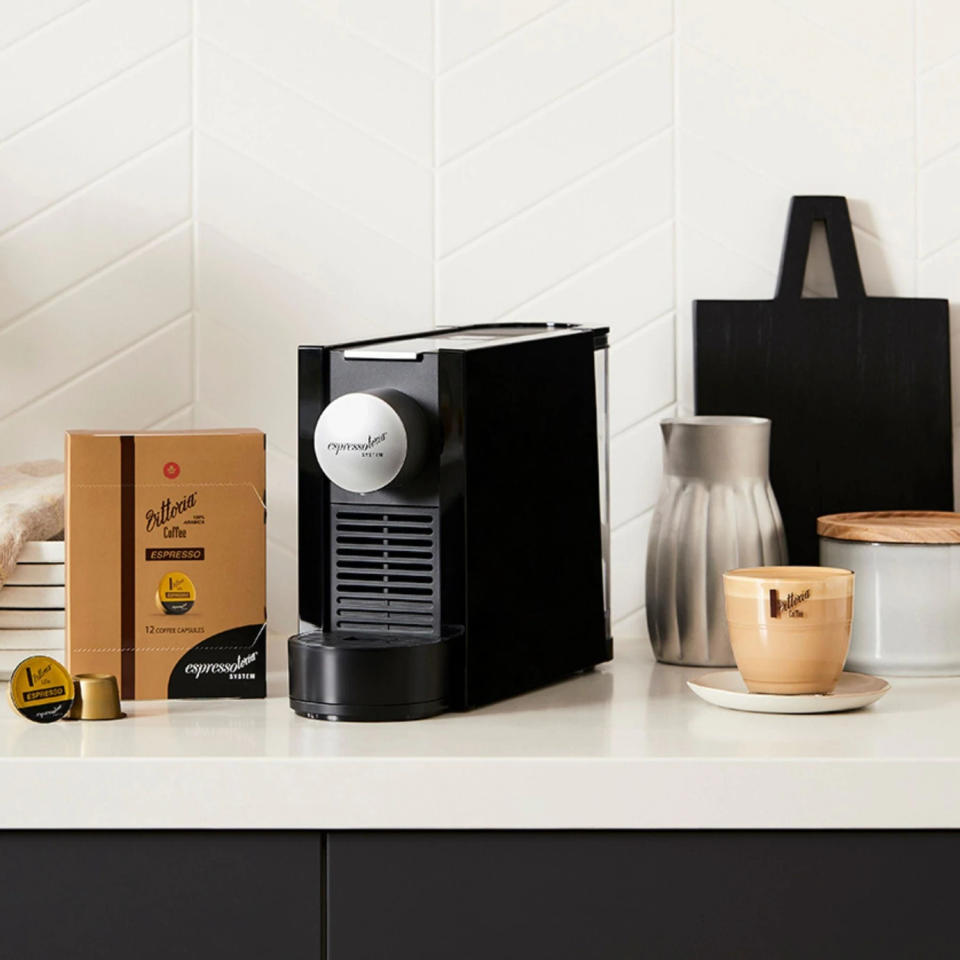 Vittoria Espressotoria Machine and pods with a flat white coffee on a white kitchen bench