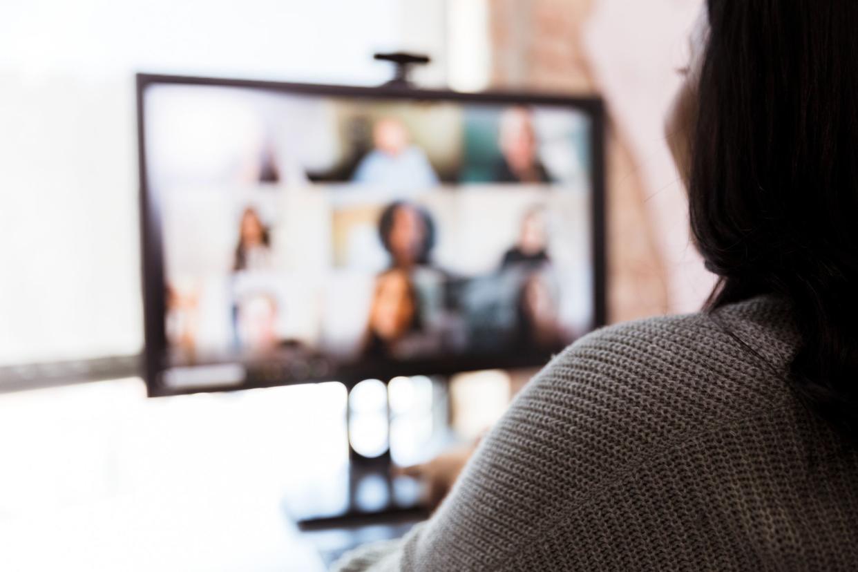 In this defocused photo, an unrecognizable woman and her team meet via video conferencing.