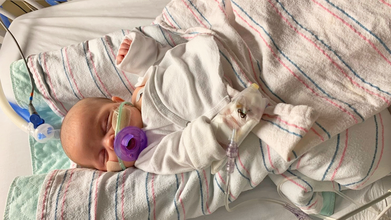 Baby hospitalized with RSV, wrapped in blankets with a purple pacifier